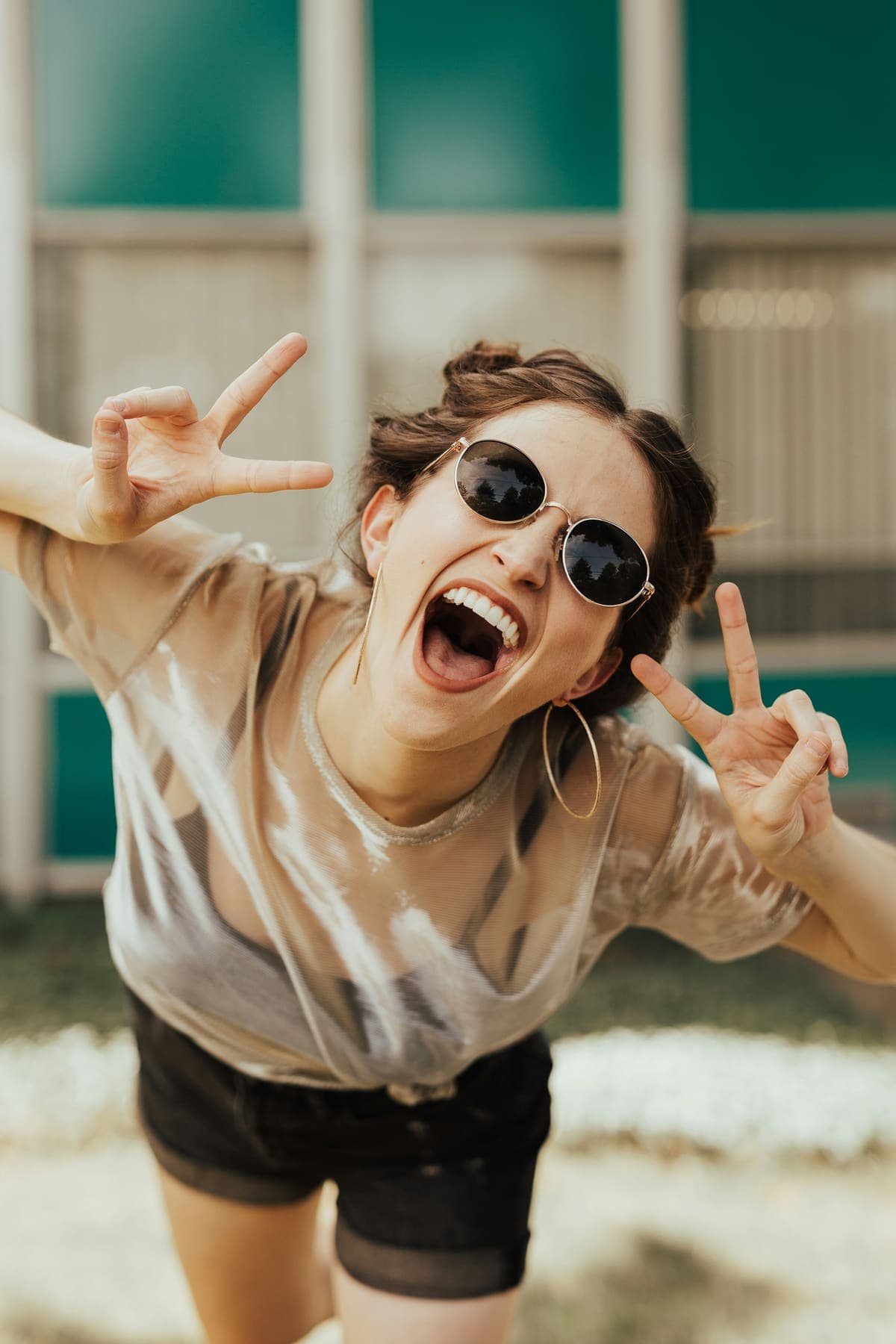 A young person flashing peace signs and laughing