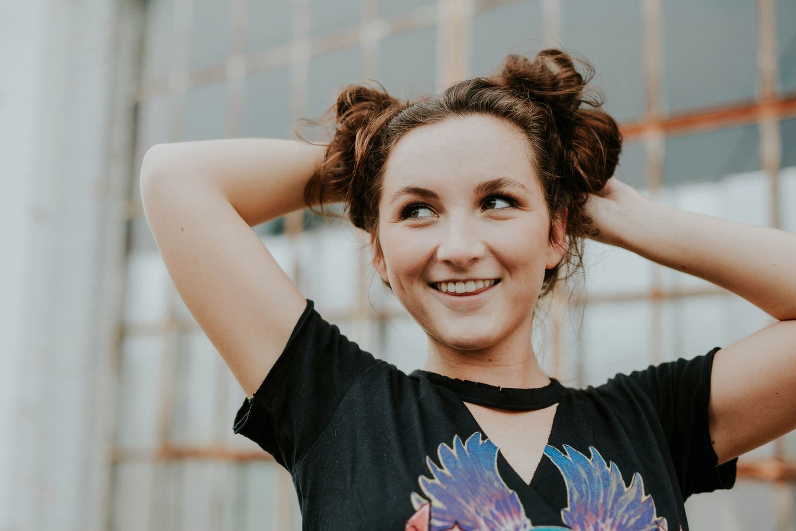 A smiling teenager holding her hair up in two buns